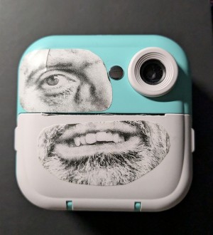 Camara de fotos para niños con un ojo y una boca impresos en blanco y negro pegados